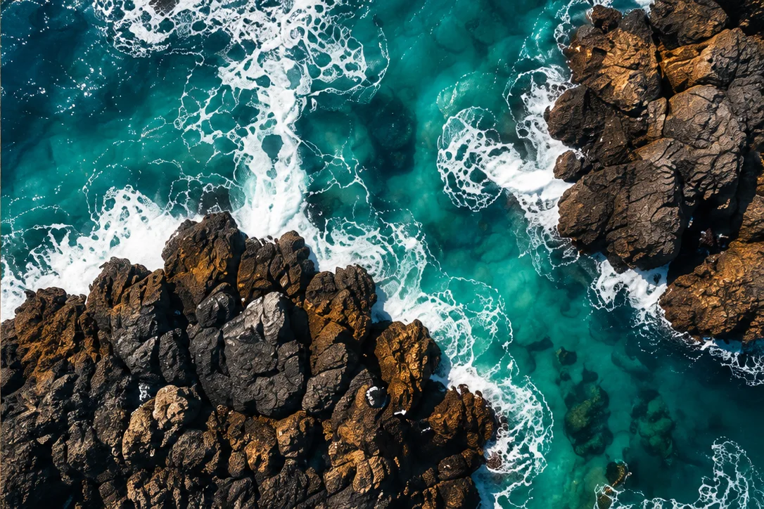 Creative aerial scene of emerald waves breaking over coastal rocks.